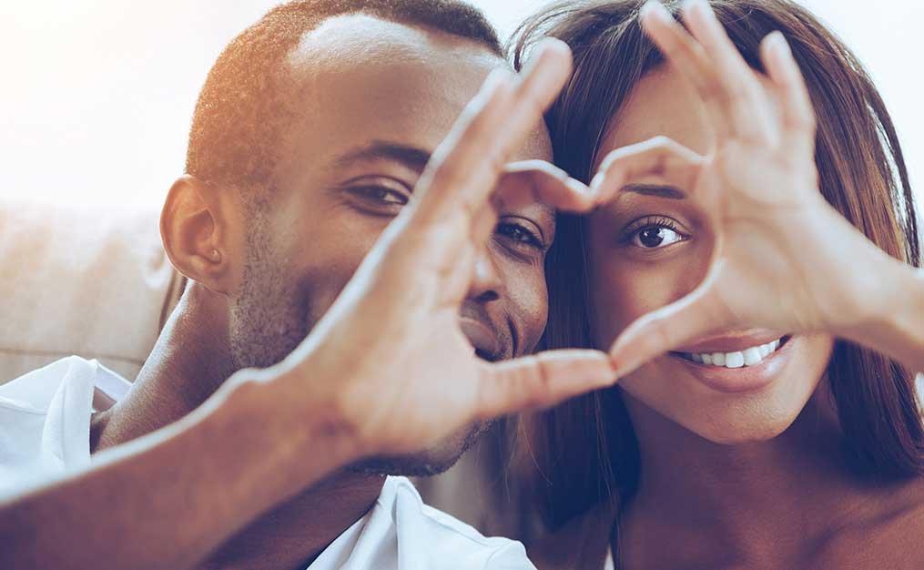 african american couple making heart sign with their hands