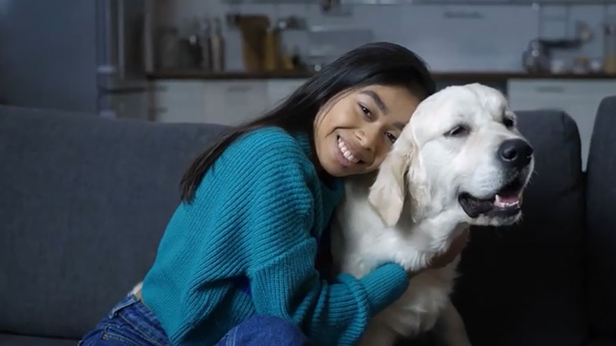 young girl on sofa hugging her dog