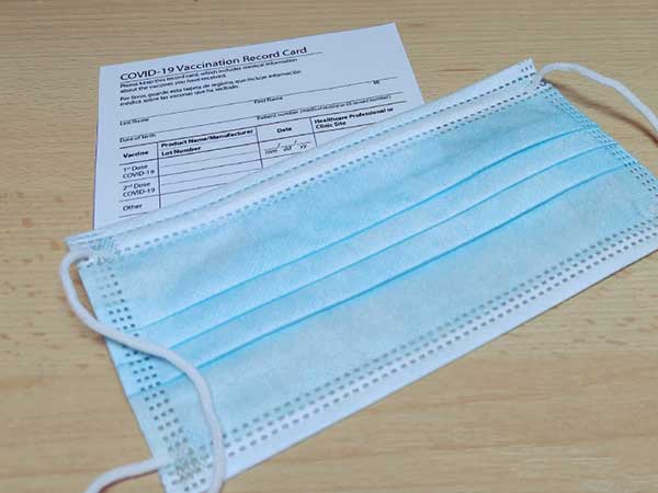 COVID vaccination card with blue protective mask