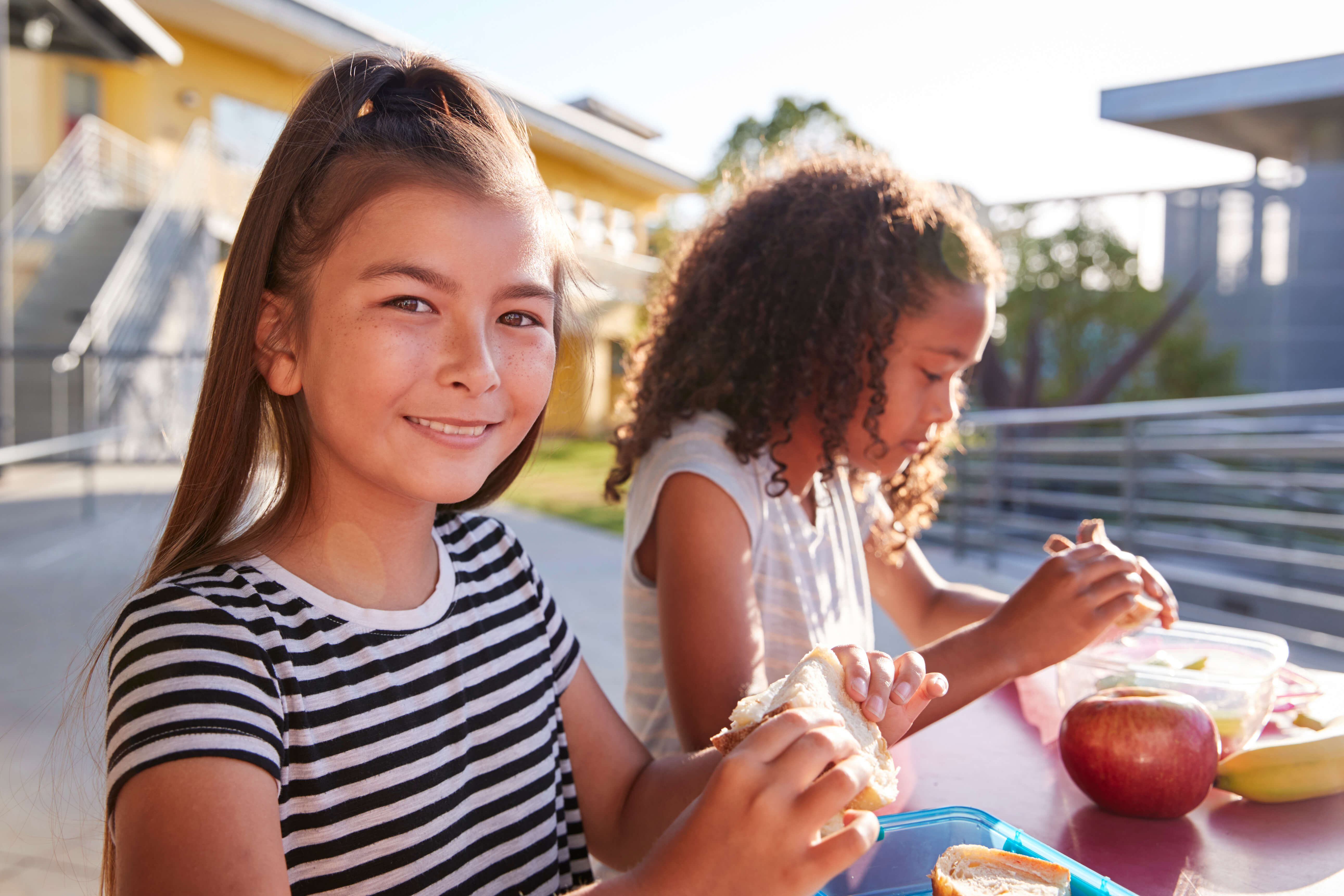 Two girls sit at lunch table smiling