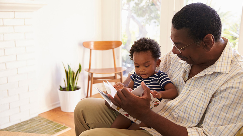 Grandfather and baby grandson reading a book together