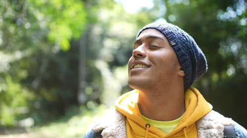 young man outside in the sun smiling