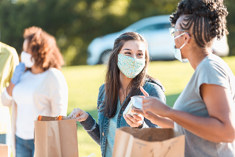 masked volunteers distribute canned food