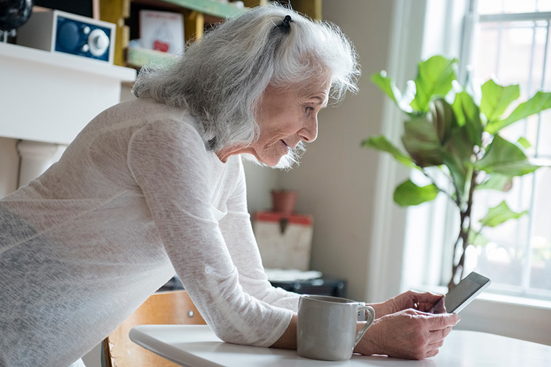 Woman looking at her cell phone while leaning on kitchen counter