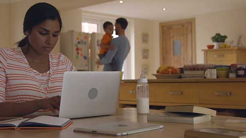 Woman working on laptop at kitchen table